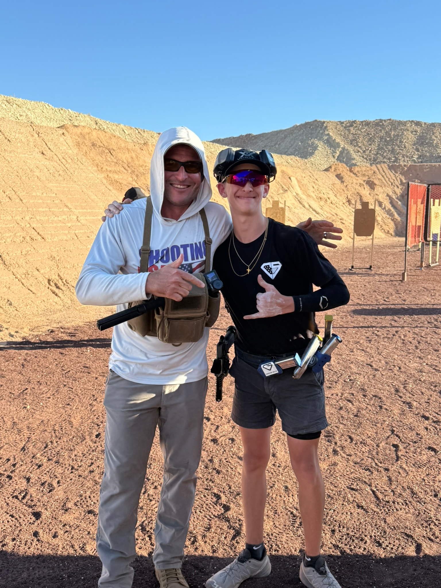 Tripp Wilson and a fellow competitor at a desert outdoor shooting range, wearing competition gear