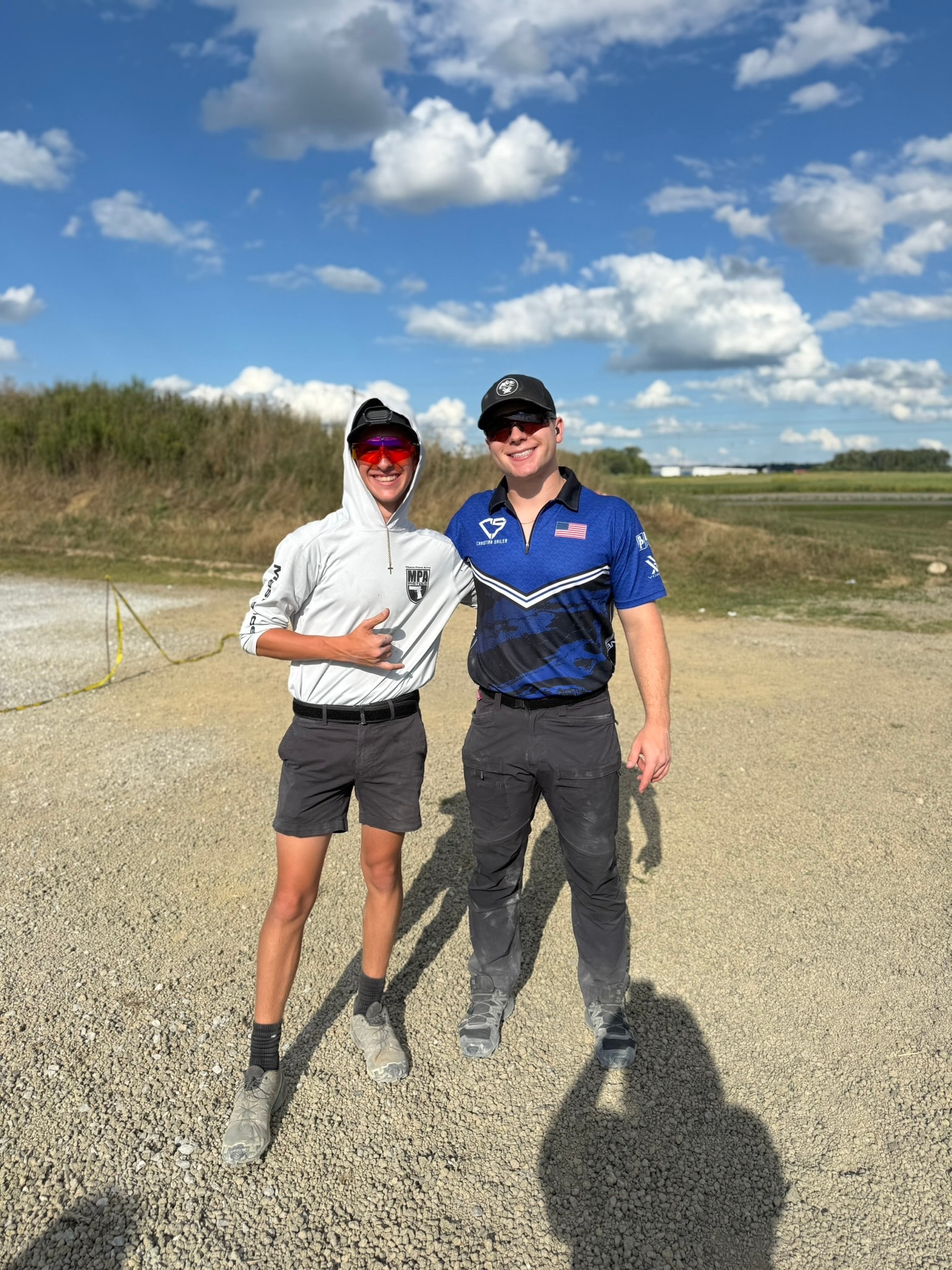 Tripp Wilson and another competitive shooter standing together at an outdoor shooting range after a match
