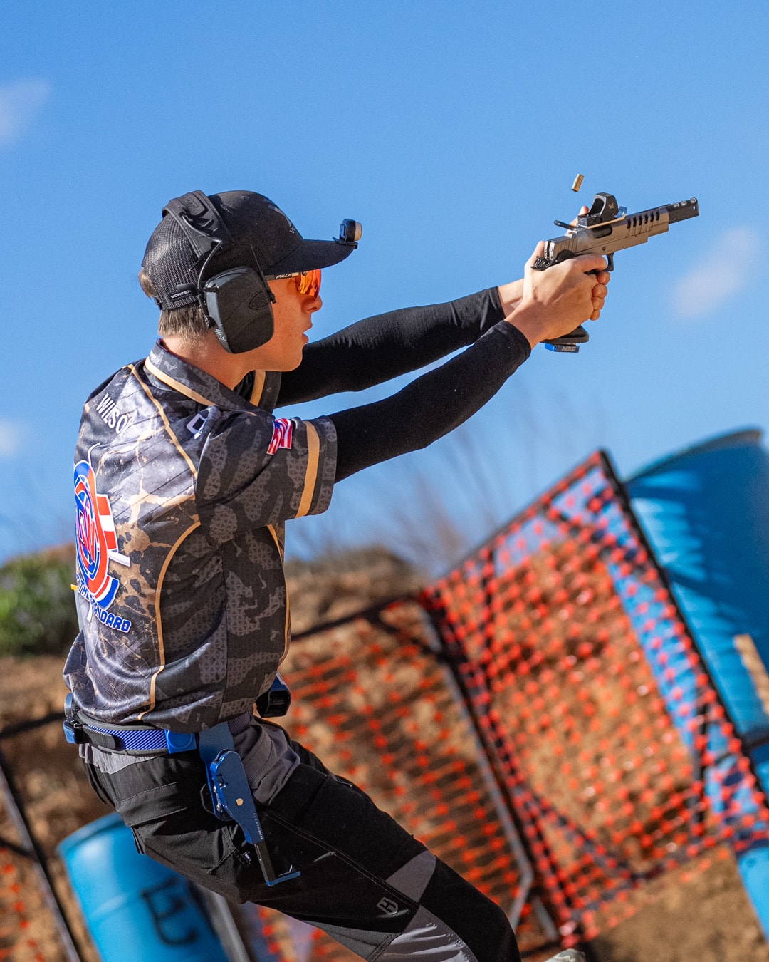 Tripp Wilson firing pistol at USPSA competition with brass casing ejecting mid-air